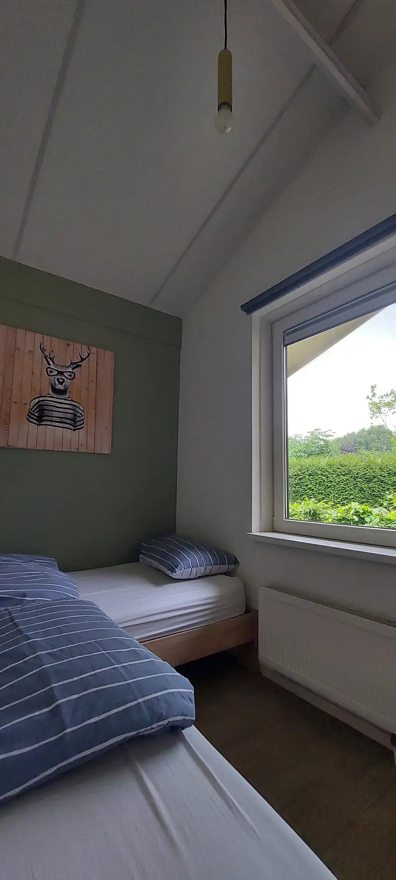 De tweede slaapkamer van huisje&nbsp;2, met twee eenpersoonsbedden en het raam met uitzicht op de haag.