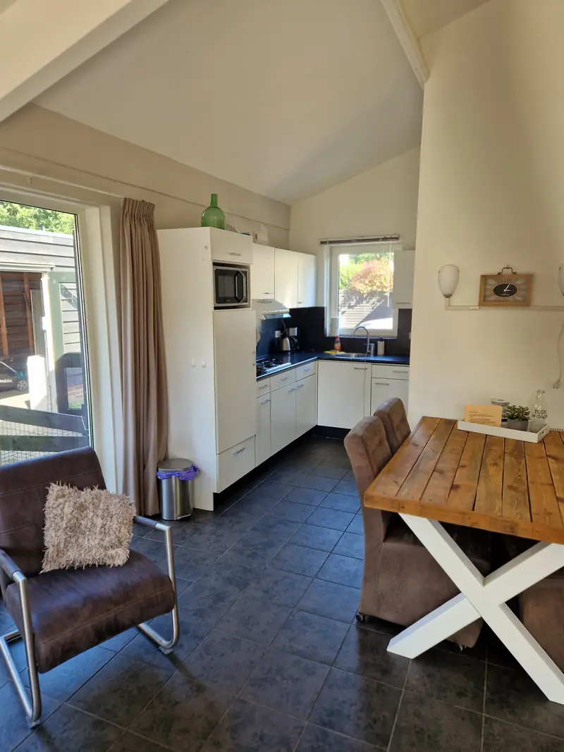 De keuken van huisje&nbsp;3, met gaskookplaat, afzuigkap, magnetron en een kleine tafel.