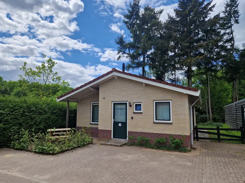 De voorkant van huisje&nbsp;3 in de zomer, onder een blauwe lucht.